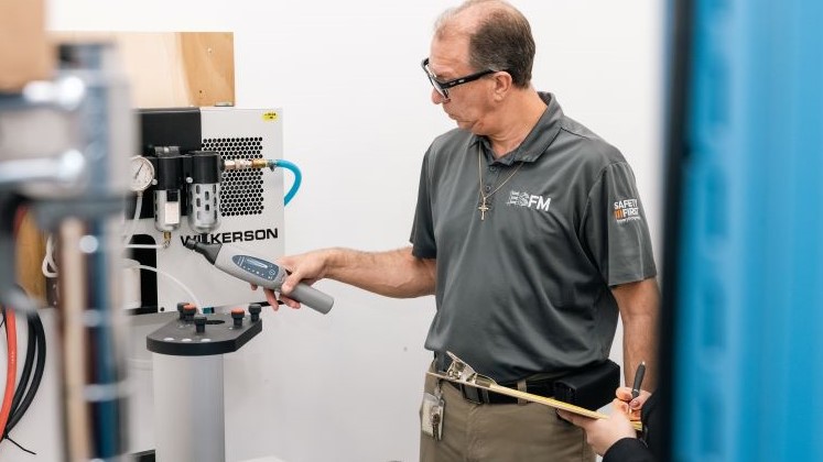 An ESFM team member checks an air compressor for leaks.