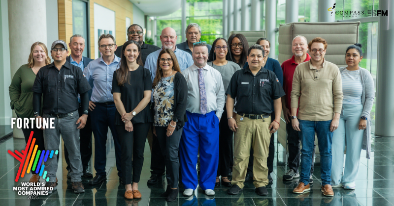 An ESFM site team poses together in a naturally lit, open facility area.